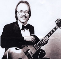 seated male guitarist in tuxedo