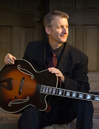 seated male guitarist in suit